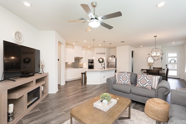 living room with sink, ceiling fan with notable chandelier, and dark hardwood / wood-style floors