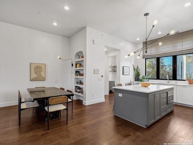 kitchen featuring a center island, stainless steel microwave, dark hardwood / wood-style floors, gray cabinets, and pendant lighting