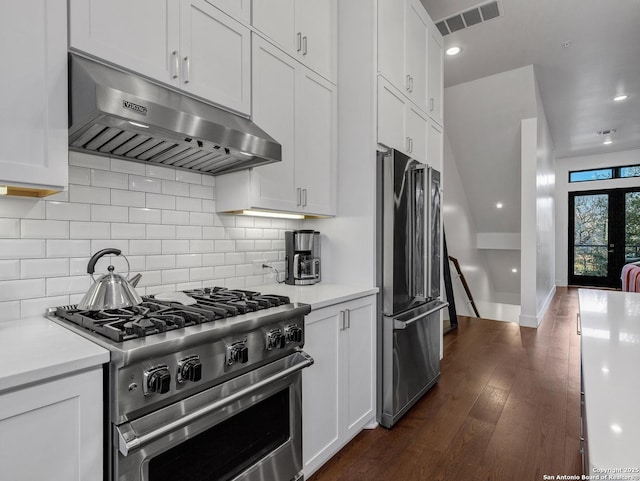 kitchen with dark wood-type flooring, appliances with stainless steel finishes, range hood, decorative backsplash, and white cabinets