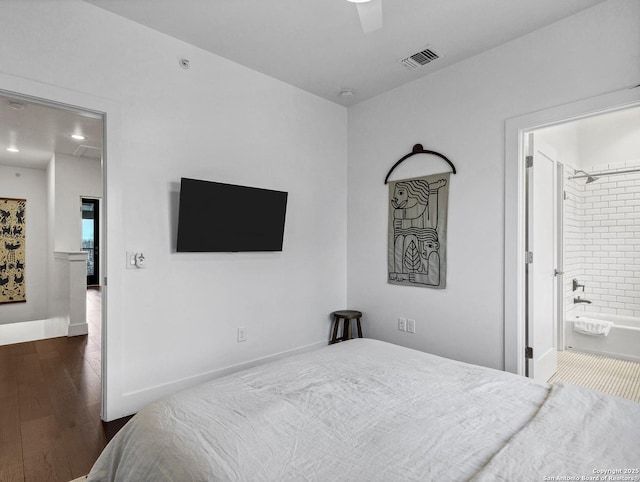 bedroom with dark wood-type flooring, ceiling fan, and connected bathroom