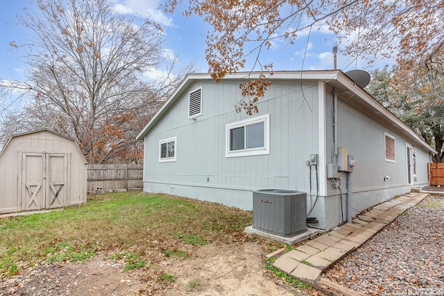 view of side of property with central AC, a lawn, and a storage unit