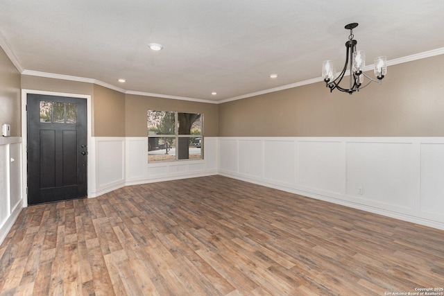 foyer entrance featuring crown molding, hardwood / wood-style flooring, and a chandelier