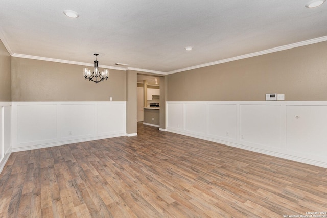 spare room with crown molding, a notable chandelier, and light wood-type flooring