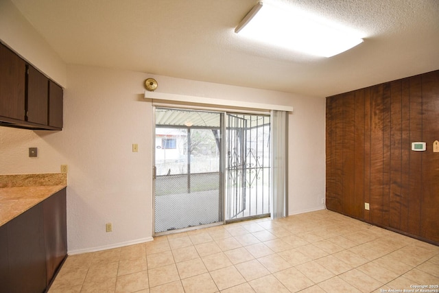 interior space featuring wooden walls, a textured ceiling, and light tile patterned floors