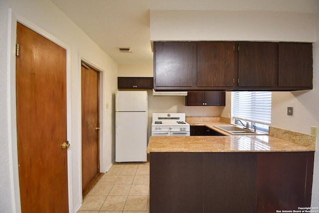 kitchen with light tile patterned flooring, sink, kitchen peninsula, white fridge, and range with two ovens