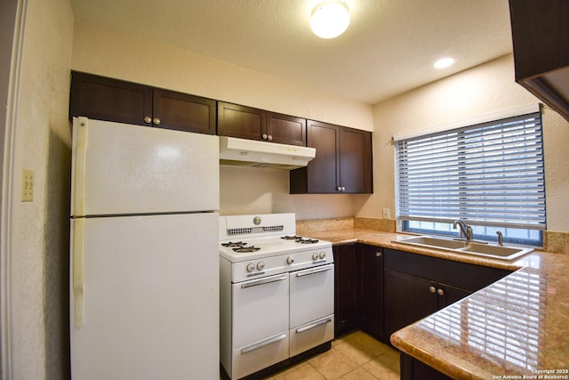 kitchen featuring light tile patterned flooring, white appliances, dark brown cabinetry, and sink