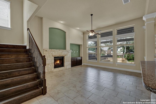 unfurnished living room featuring light tile patterned flooring, a stone fireplace, and ceiling fan