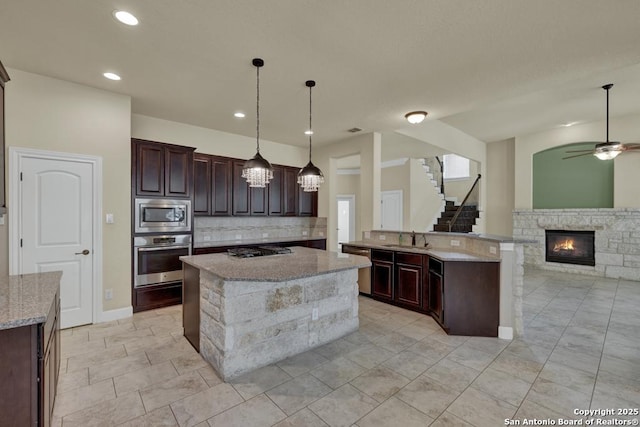 kitchen with sink, decorative light fixtures, dark brown cabinets, a center island with sink, and appliances with stainless steel finishes