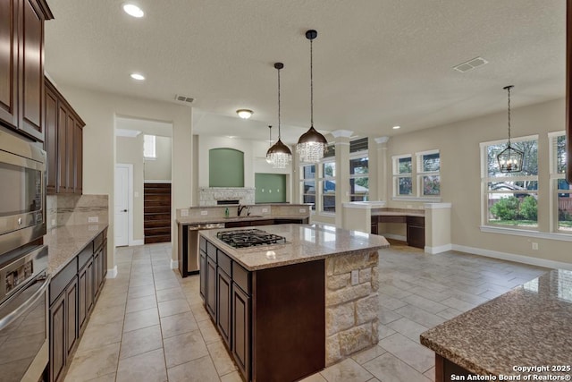 kitchen with tasteful backsplash, decorative light fixtures, stainless steel appliances, and a center island