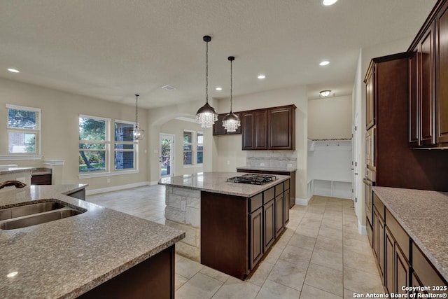 kitchen featuring sink, a center island, dark brown cabinets, appliances with stainless steel finishes, and pendant lighting