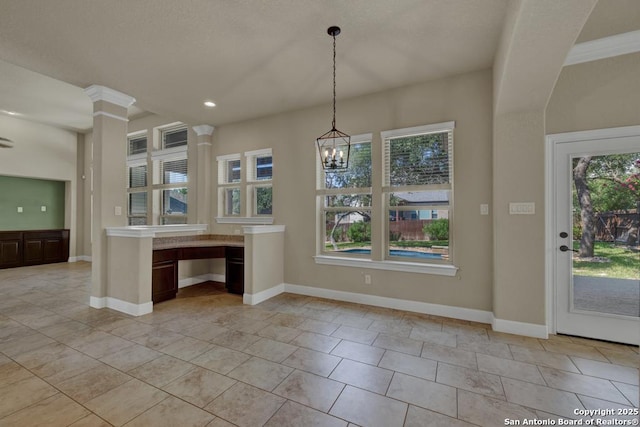 kitchen with hanging light fixtures, light tile patterned floors, a wealth of natural light, and ornate columns