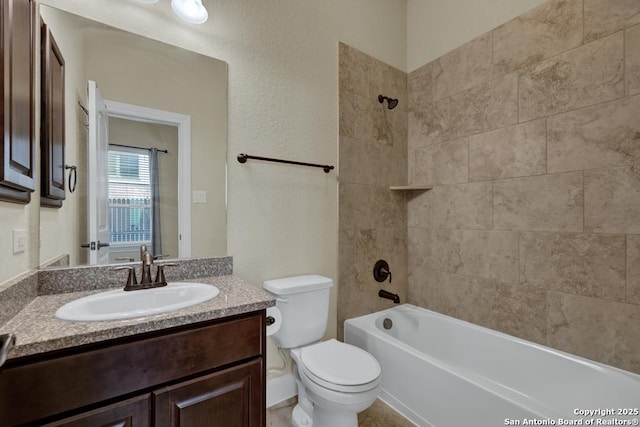 full bathroom with vanity, tiled shower / bath, and toilet