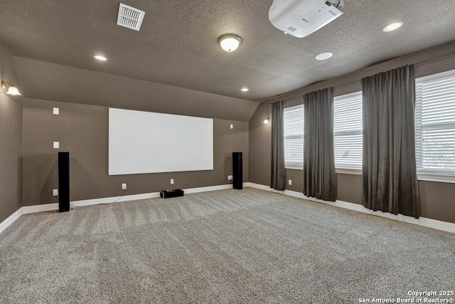 cinema room featuring vaulted ceiling, a textured ceiling, and carpet flooring