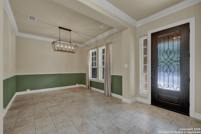 foyer entrance featuring ornamental molding, plenty of natural light, and an inviting chandelier