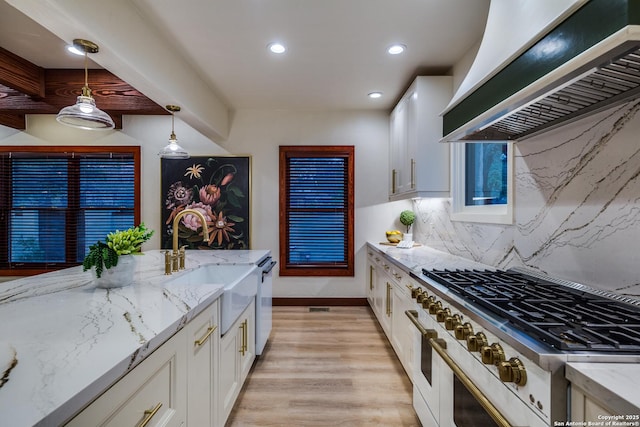 kitchen with pendant lighting, appliances with stainless steel finishes, light stone countertops, white cabinets, and custom exhaust hood