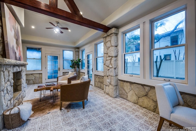 living area with ceiling fan, a fireplace, and beam ceiling