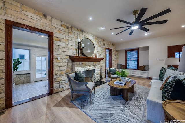 living room featuring ceiling fan, a fireplace, and light hardwood / wood-style flooring