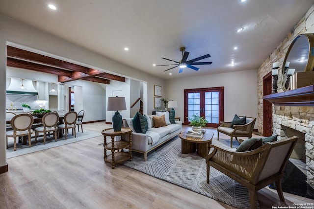 living room featuring french doors, ceiling fan, a fireplace, and light wood-type flooring