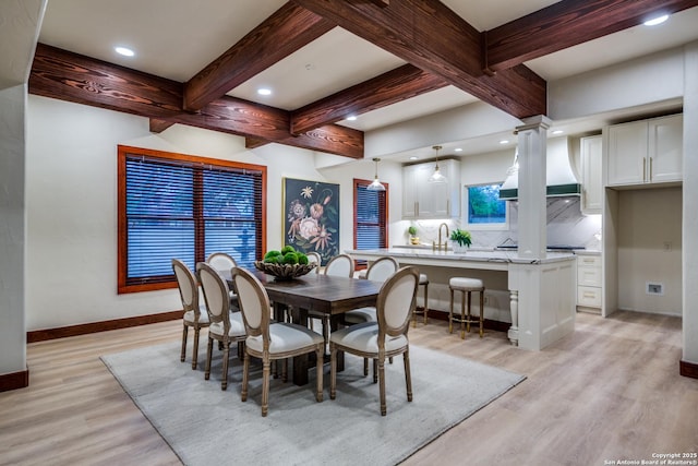 dining space with beamed ceiling, sink, and light hardwood / wood-style floors