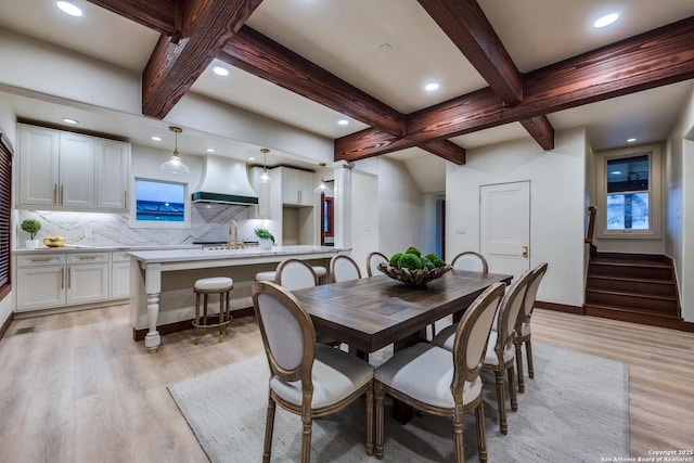 dining room featuring beam ceiling and light hardwood / wood-style floors