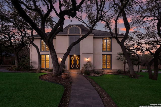 tudor-style house with a lawn and french doors