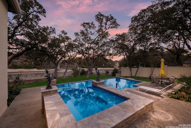 pool at dusk with a patio area