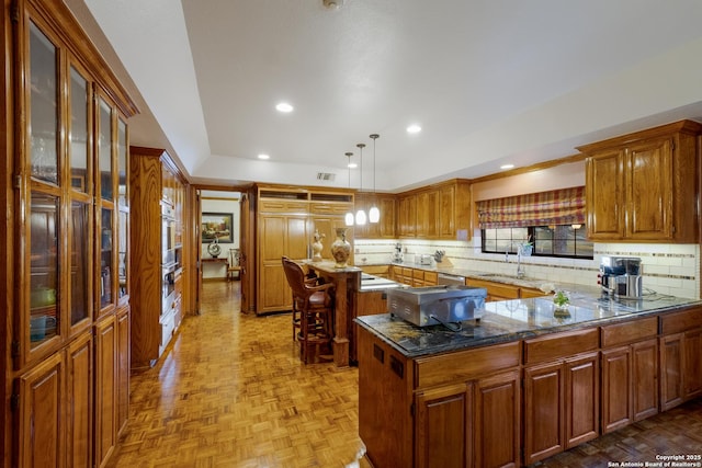 kitchen with sink, decorative light fixtures, dark stone countertops, a kitchen island, and light parquet floors