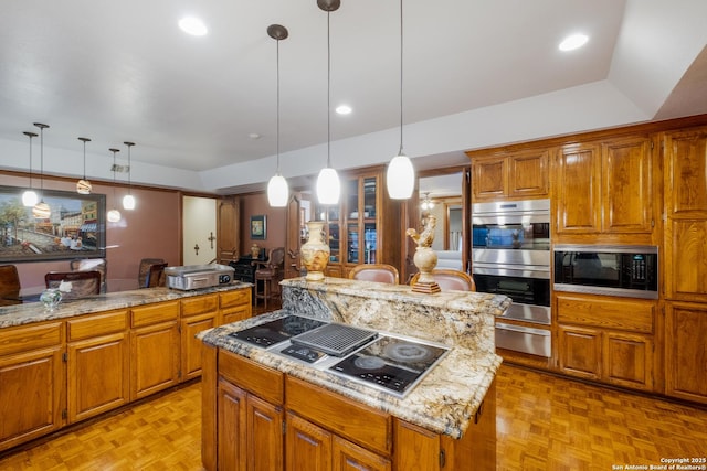 kitchen featuring light parquet floors, light stone countertops, black appliances, a kitchen island, and decorative light fixtures