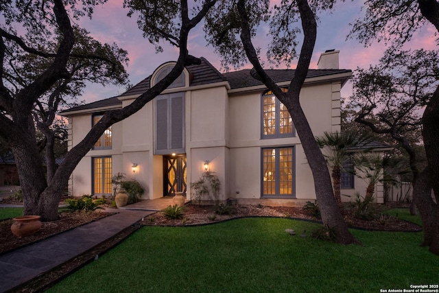 back house at dusk featuring a yard