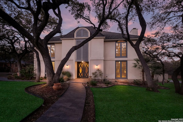 tudor-style house with a lawn and french doors