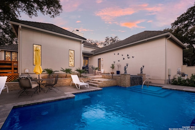 pool at dusk with a patio area