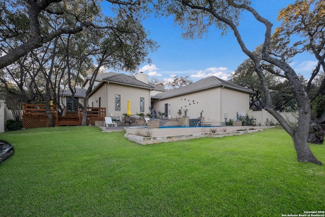 rear view of property featuring a yard and a swimming pool side deck