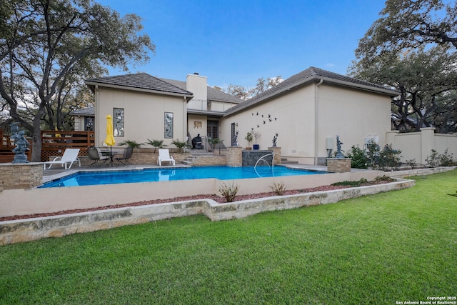 back of house with pool water feature and a lawn