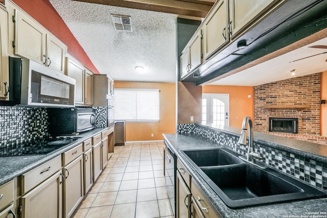 kitchen with tasteful backsplash, sink, light tile patterned floors, black appliances, and a textured ceiling