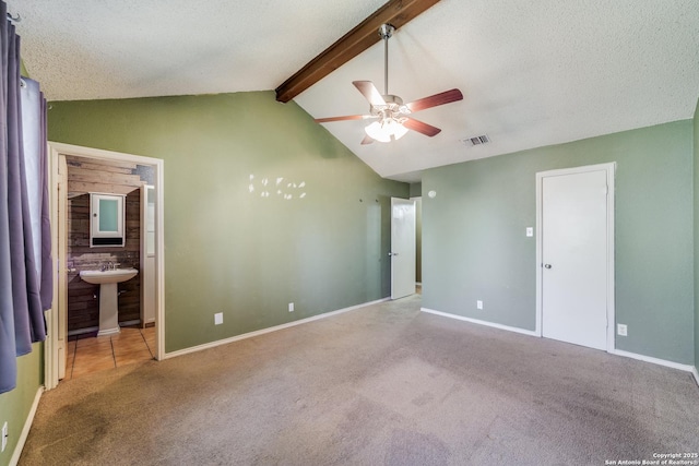 unfurnished bedroom featuring carpet floors, lofted ceiling with beams, a textured ceiling, and ensuite bathroom