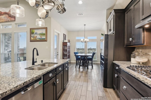 kitchen with light stone countertops, appliances with stainless steel finishes, sink, and dark brown cabinets