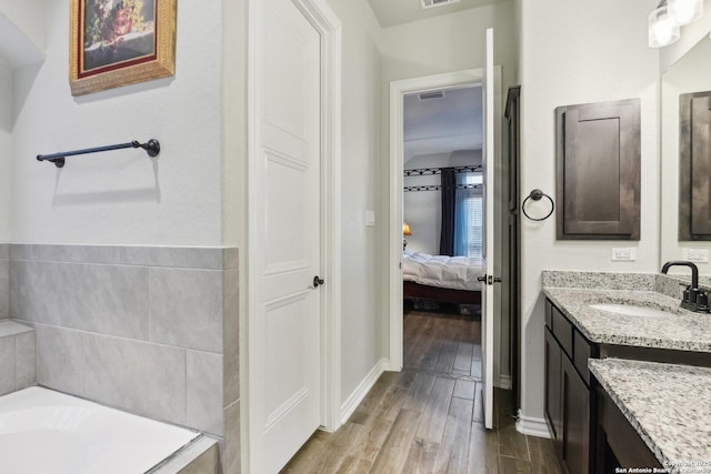 bathroom featuring hardwood / wood-style flooring, vanity, and a washtub