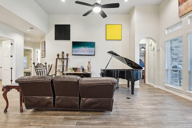 living room with wood-type flooring, a towering ceiling, and ceiling fan