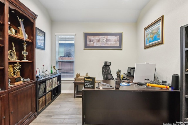 office space with vaulted ceiling and light hardwood / wood-style flooring