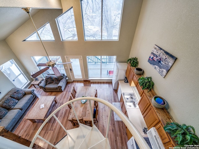 living room featuring ceiling fan, high vaulted ceiling, light hardwood / wood-style floors, and a skylight