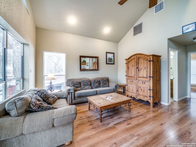 living room featuring high vaulted ceiling, light hardwood / wood-style floors, and a wealth of natural light