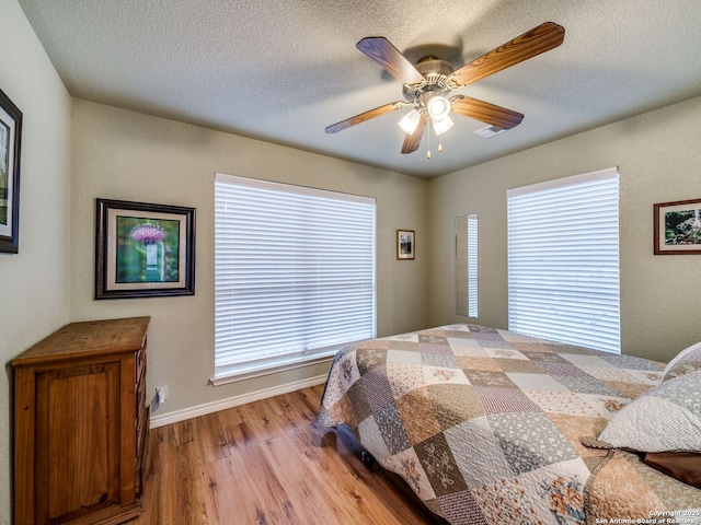 bedroom with ceiling fan, a textured ceiling, and light hardwood / wood-style floors