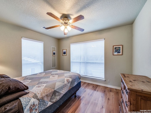 bedroom featuring hardwood / wood-style floors, a textured ceiling, and ceiling fan