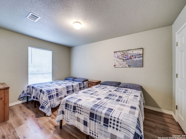 bedroom with hardwood / wood-style floors and a textured ceiling