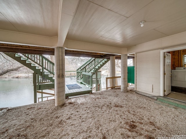 interior space featuring a water view, washer / dryer, and carpet flooring