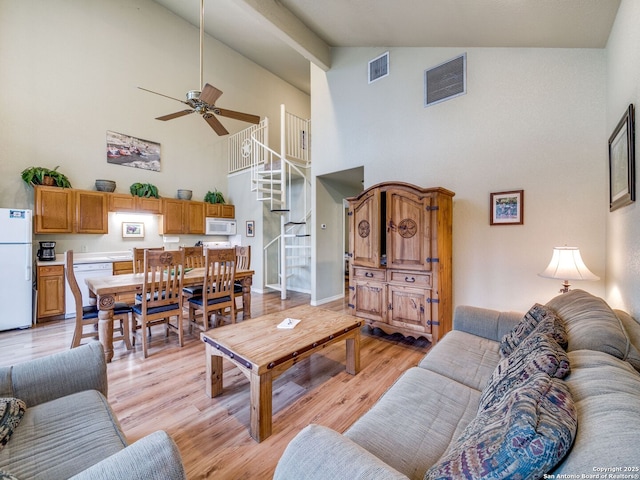 living room with high vaulted ceiling, ceiling fan, and light wood-type flooring