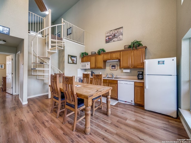 dining space with a towering ceiling, sink, and light wood-type flooring