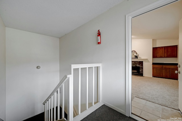 staircase with carpet and a textured ceiling