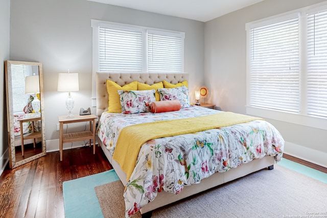 bedroom with multiple windows and dark wood-type flooring