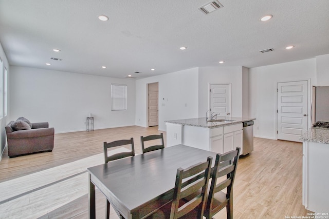 dining room featuring sink, a textured ceiling, and light wood-type flooring